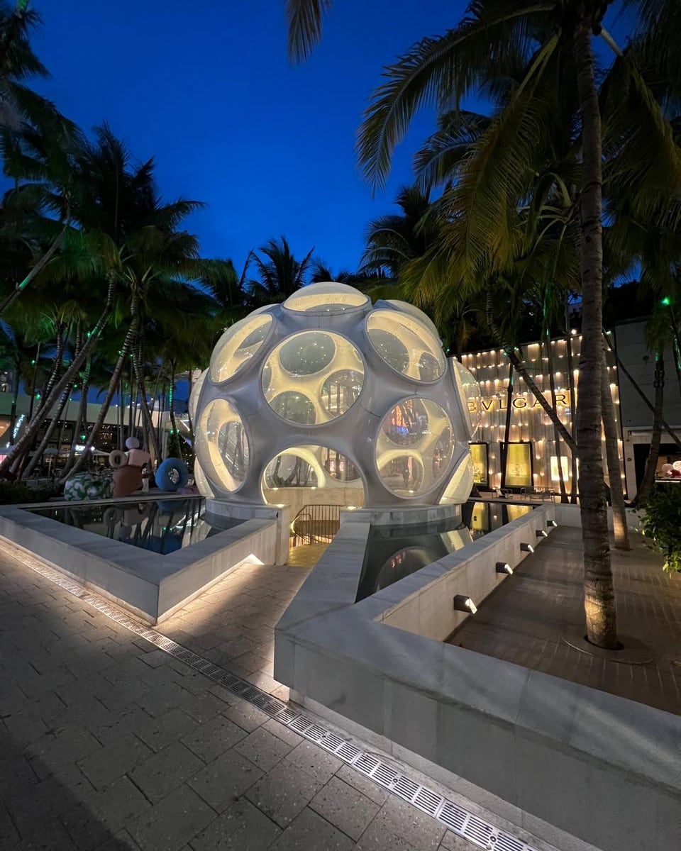Domo de vidro iluminado no Palm Court do Miami Design District, ao anoitecer