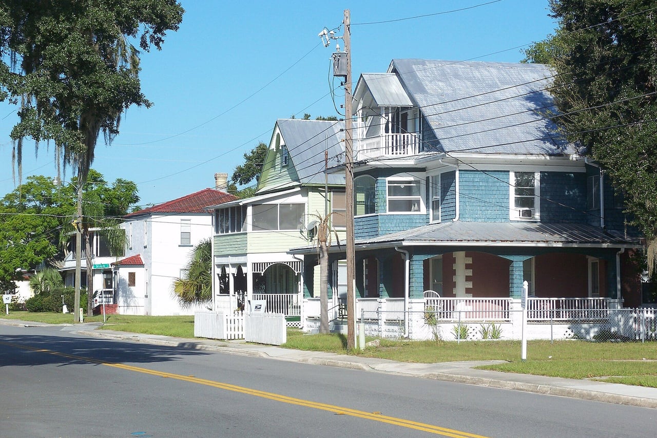 Casas antigas de madeira com varanda numa rua arborizada