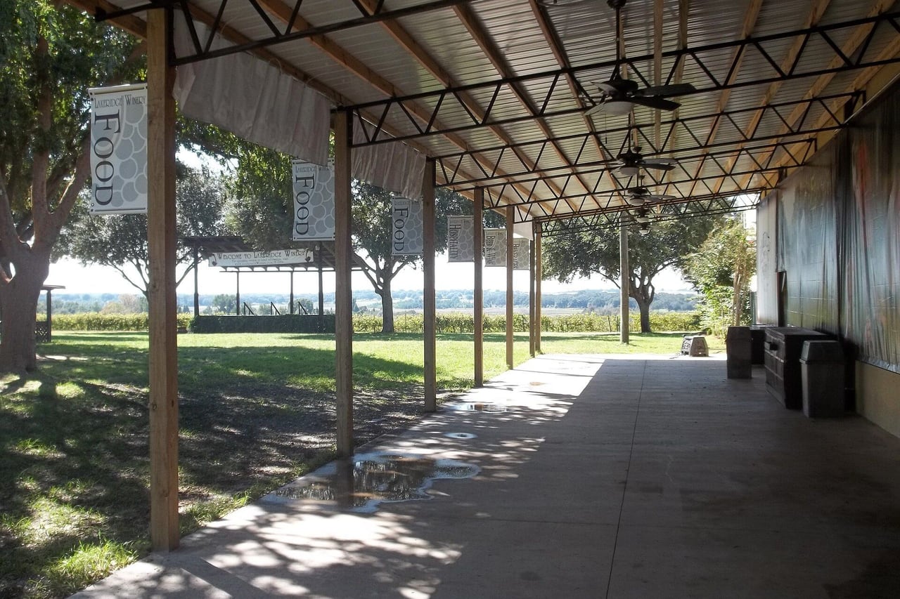 Varanda coberta com ventiladores de teto voltada para gramado e vinhedos.